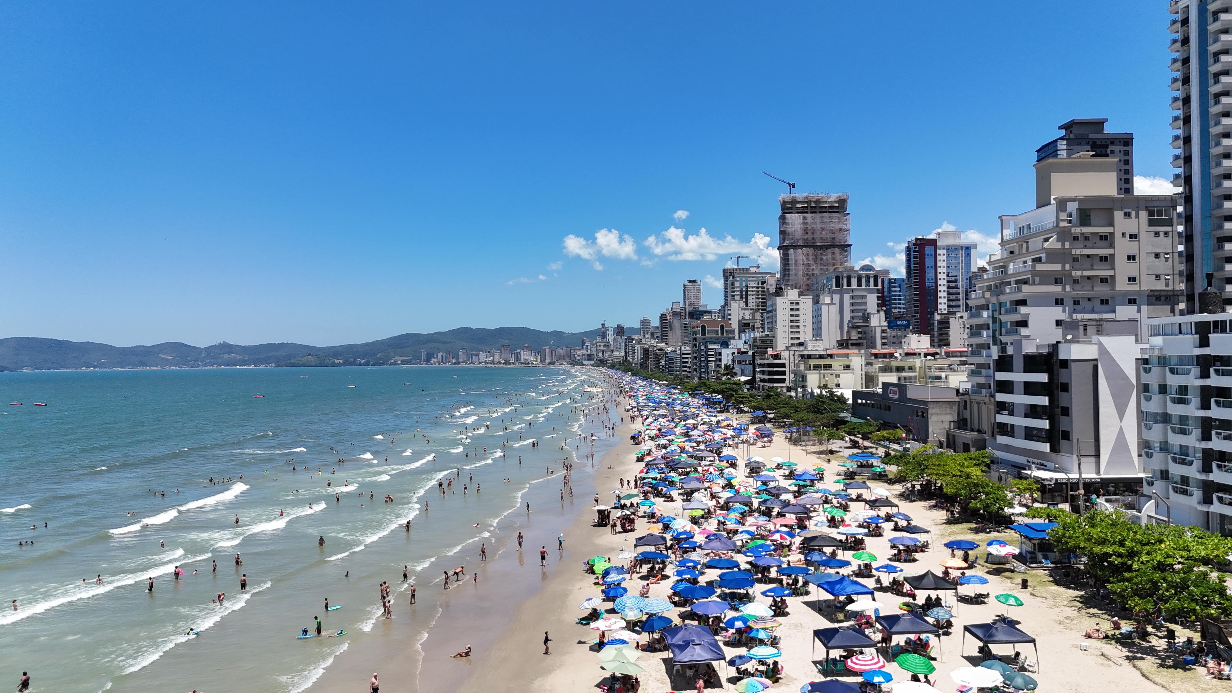 Praia de Itapema com muitos guarda-sóis e edifícios